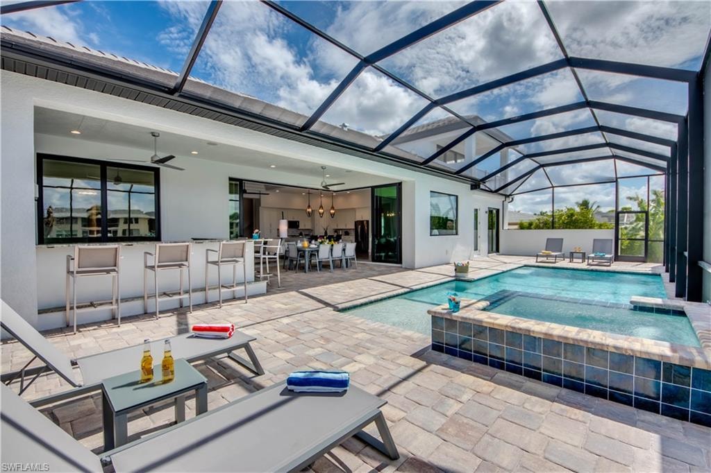 View of pool featuring a water view, a pool with connected hot tub, a lanai, and a patio area