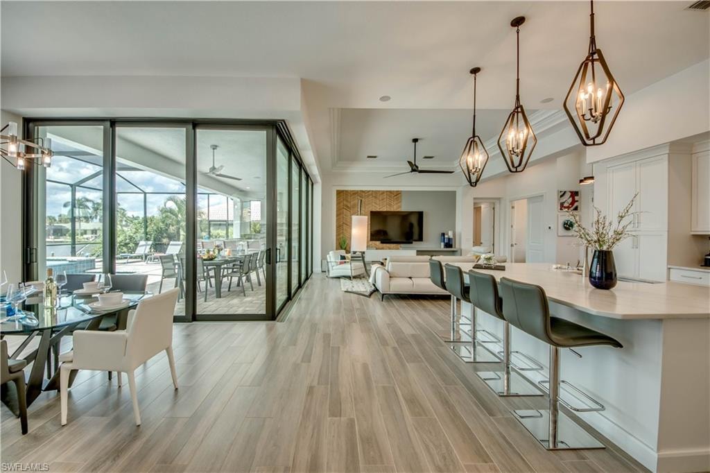 Kitchen featuring appliances with stainless steel finishes, white cabinetry, wood tiled floors, hanging light fixtures, and recessed lighting
