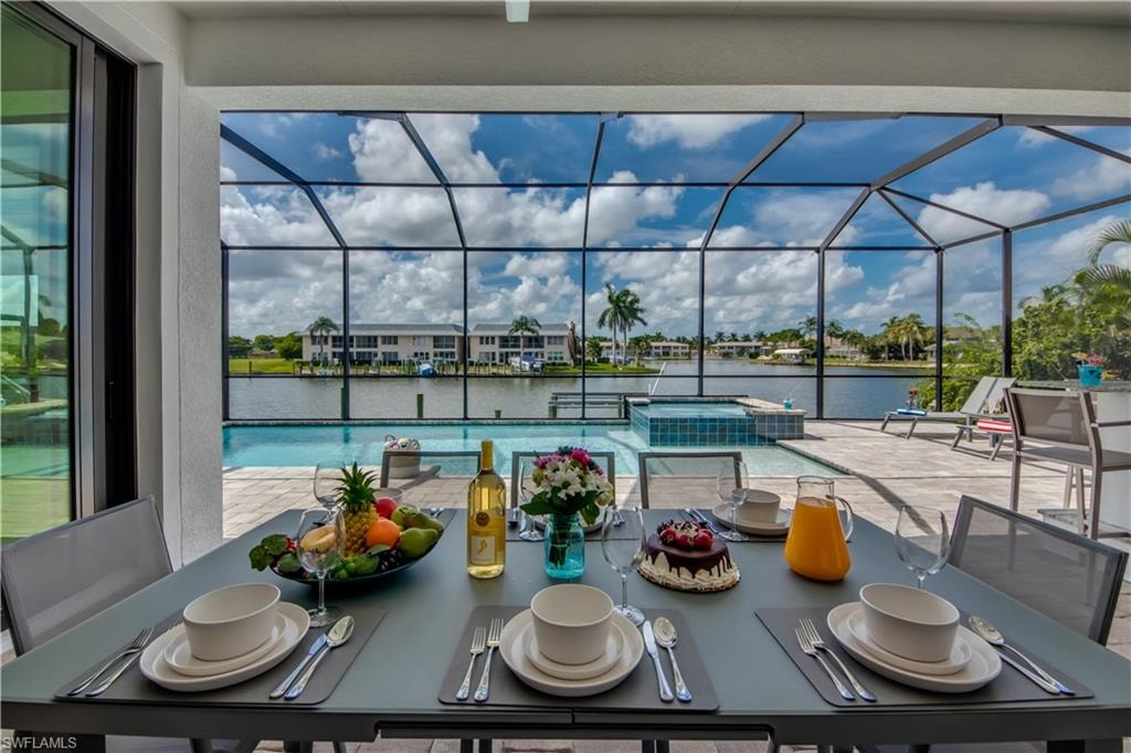 View of patio / terrace featuring a sunroom, outdoor dining area, a water view, and a ceiling fan