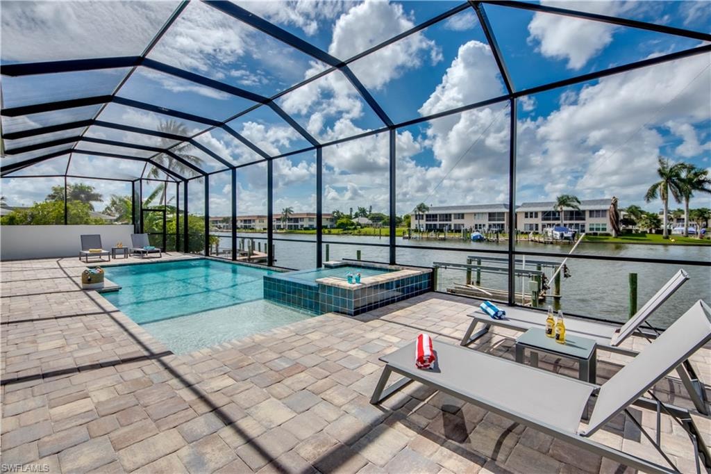 View of patio / terrace with a sunroom, a jacuzzi, a lanai, and a water view