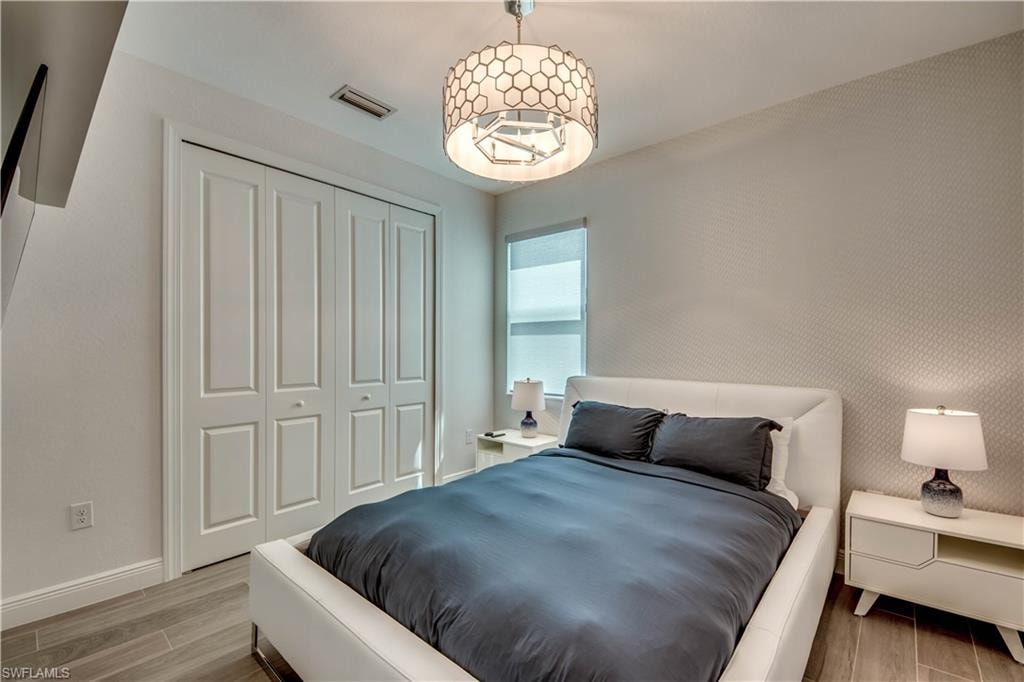 Washroom with washing machine and dryer, wood tiled floors, cabinet space, wallpapered walls, and recessed lighting