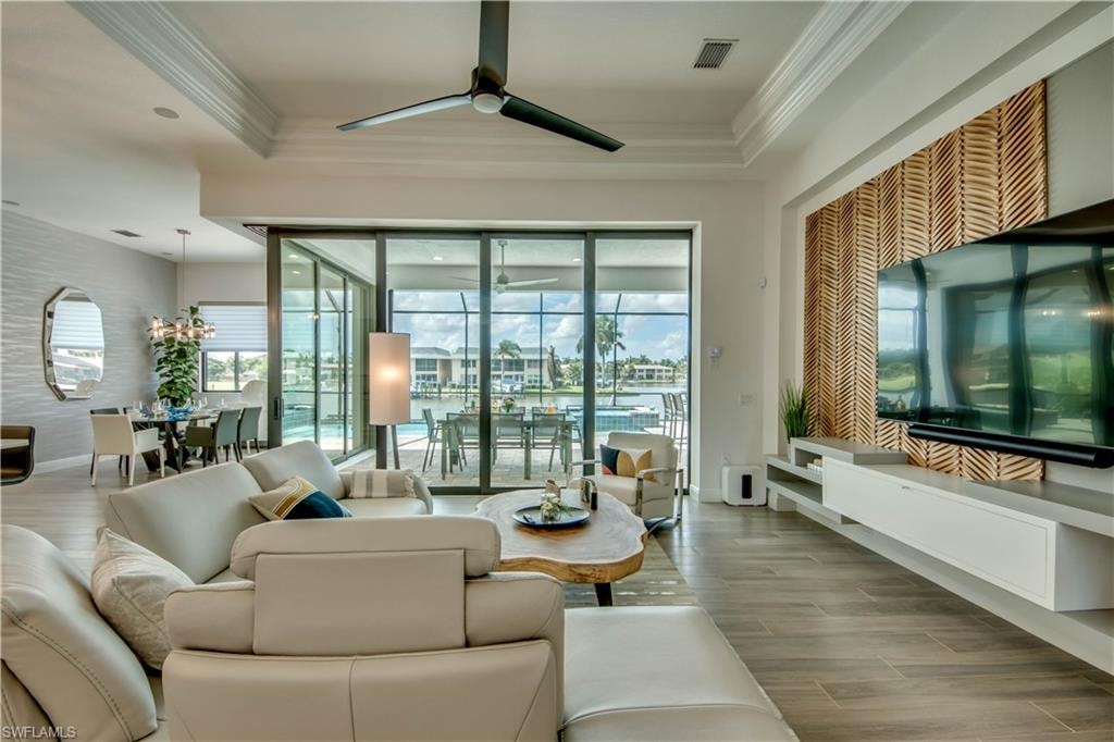 Living room with wood tiled floors, a sunroom, a ceiling fan, and crown molding