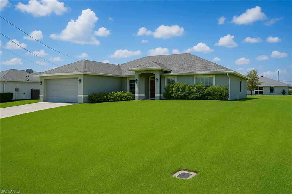 Ranch-style home with a front yard, stucco siding, concrete driveway, and a garage