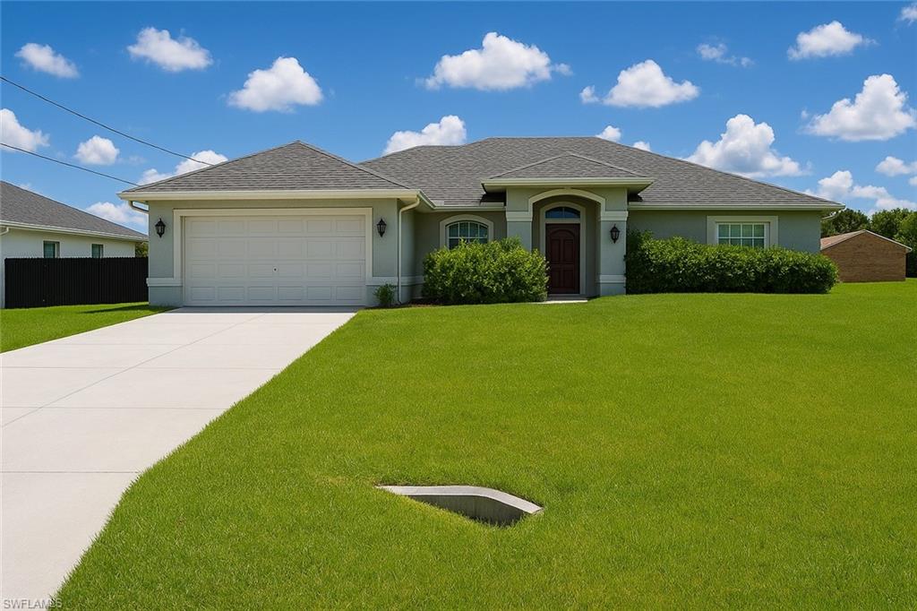 Ranch-style home featuring stucco siding, a front lawn, a garage, and driveway