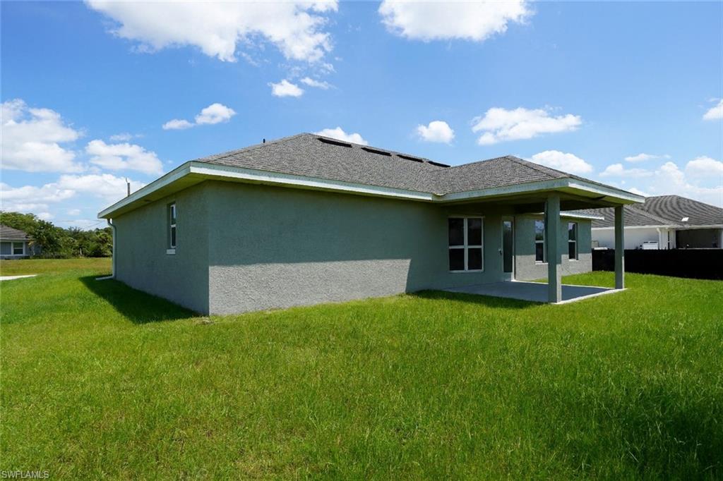 Back of property featuring a lawn, a patio, and stucco siding
