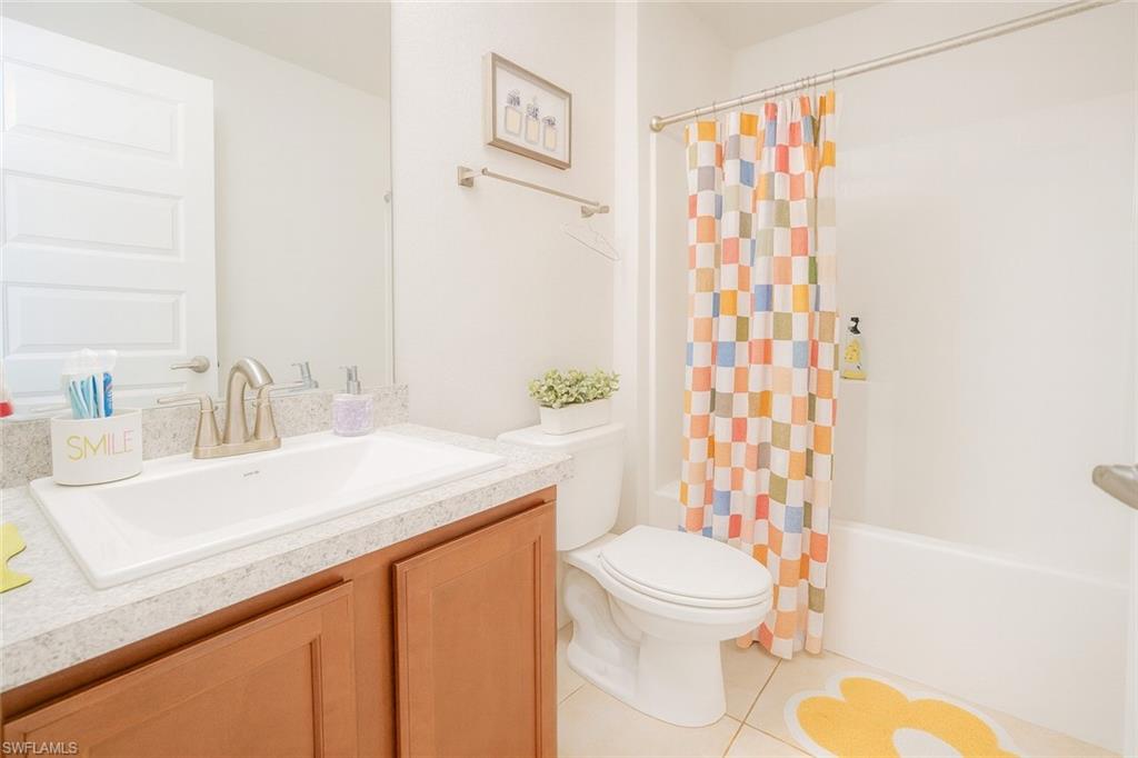 Full bathroom with vanity, shower / bath combo with shower curtain, and light tile patterned floors