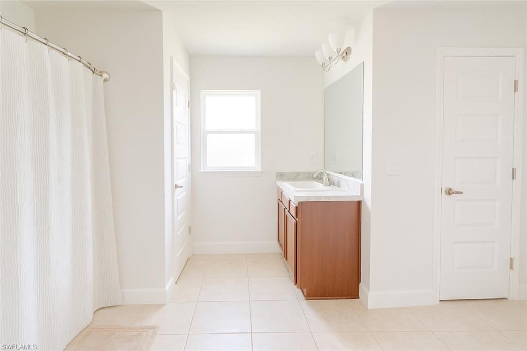 Full bathroom with vanity, a shower with curtain, and light tile patterned floors
