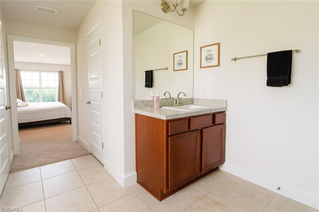 Ensuite bathroom featuring vanity, light tile patterned flooring, and light carpet