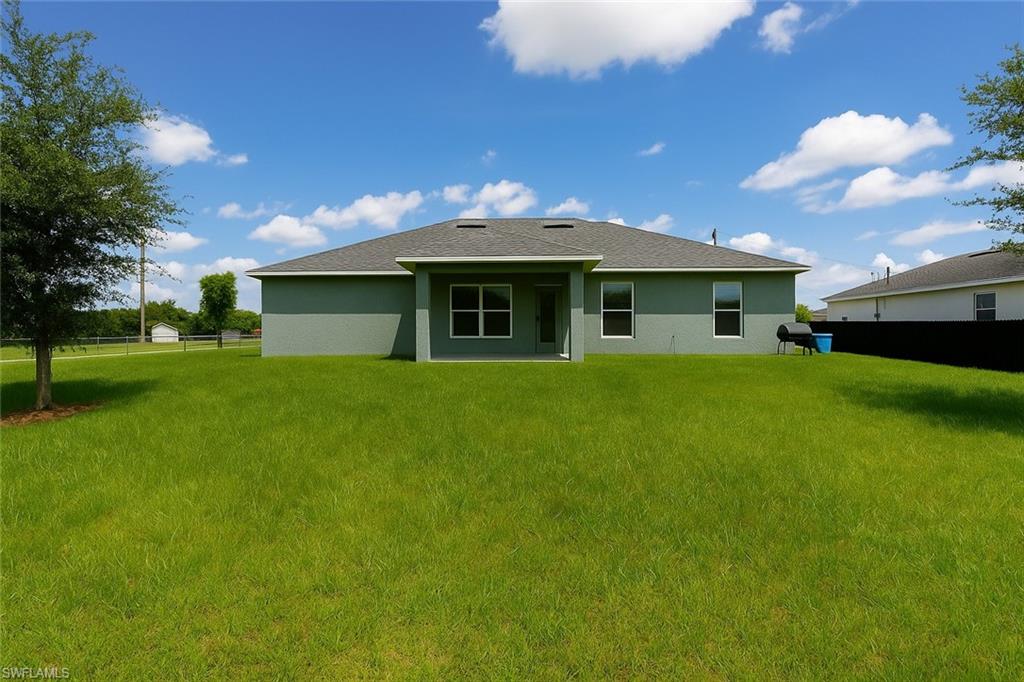 Rear view of house featuring a patio area, stucco siding, and a shingled roof