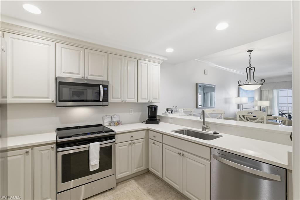 Kitchen with stainless steel appliances, recessed lighting, decorative light fixtures, light tile patterned flooring, and a peninsula