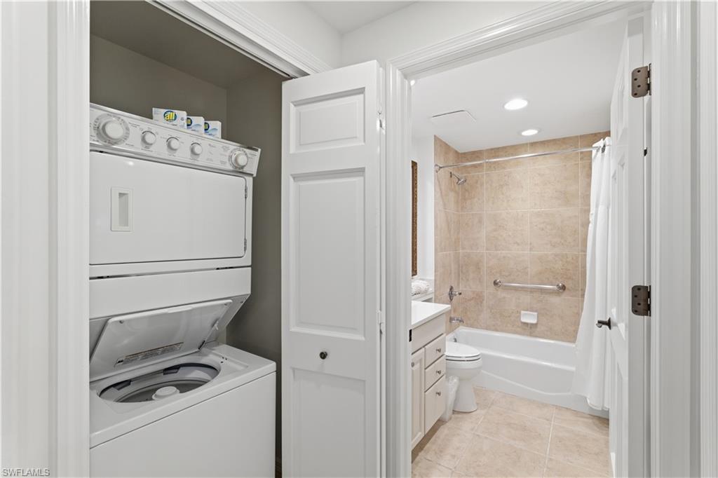 Laundry room featuring stacked washer and clothes dryer and light tile patterned floors