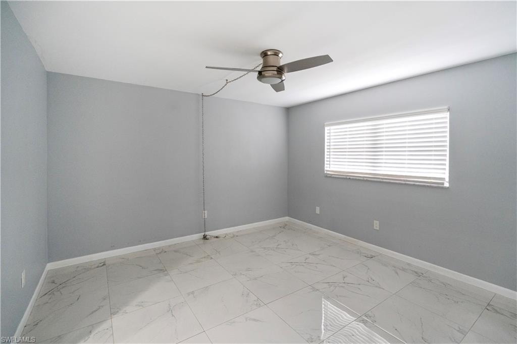 Unfurnished room featuring light marble finish floors and a ceiling fan