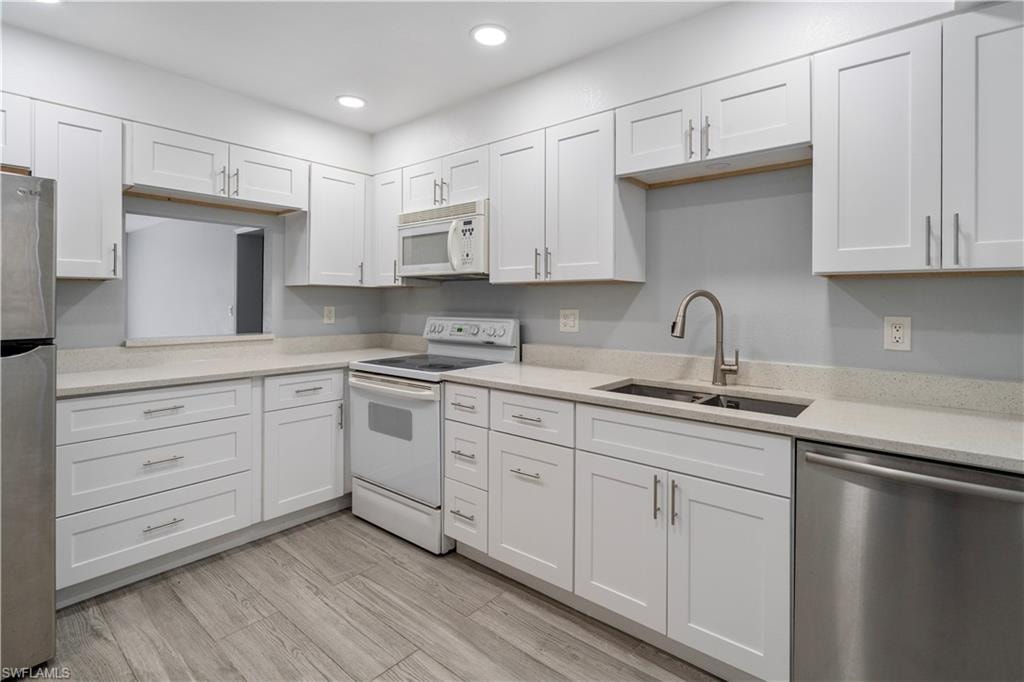 Kitchen featuring appliances with stainless steel finishes, white cabinets, light stone counters, and recessed lighting