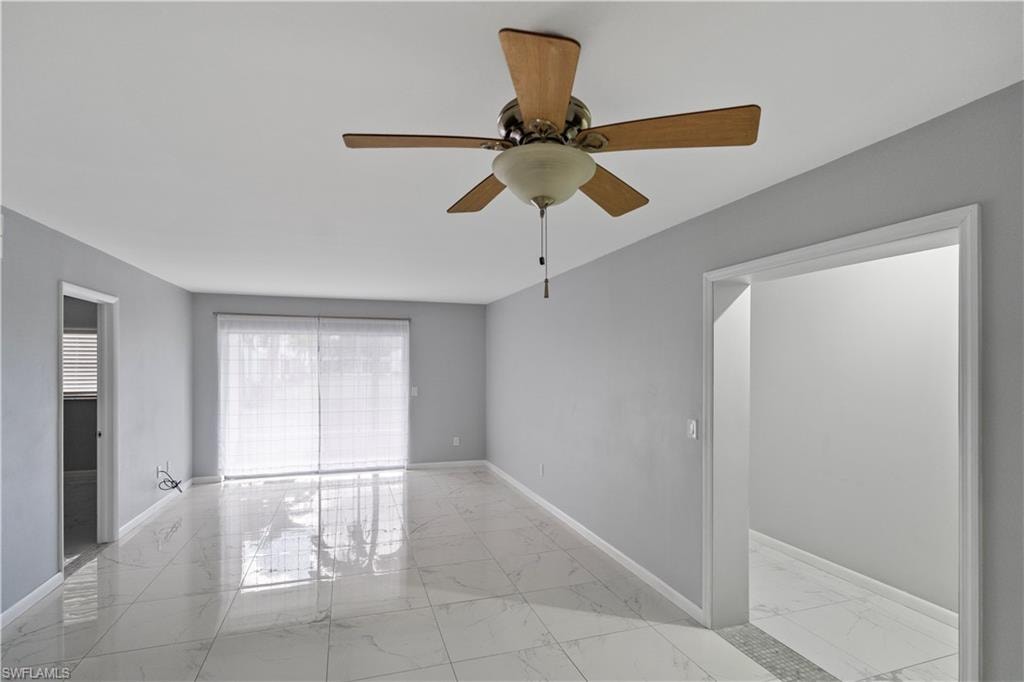 Unfurnished room featuring light marble finish flooring and a ceiling fan