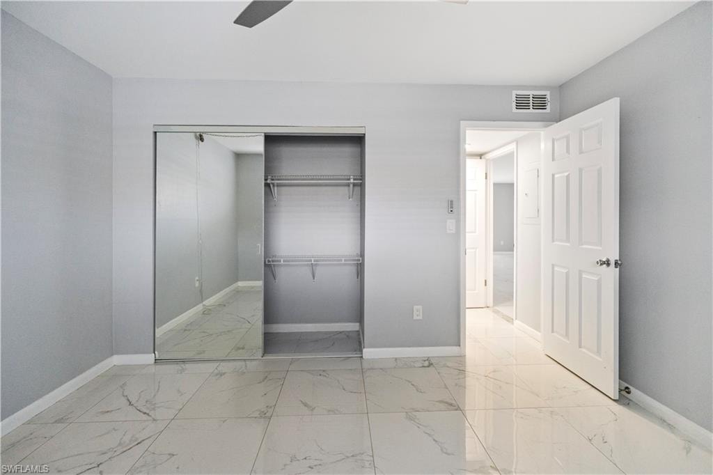 Unfurnished bedroom featuring light marble finish floors, a closet, and ceiling fan