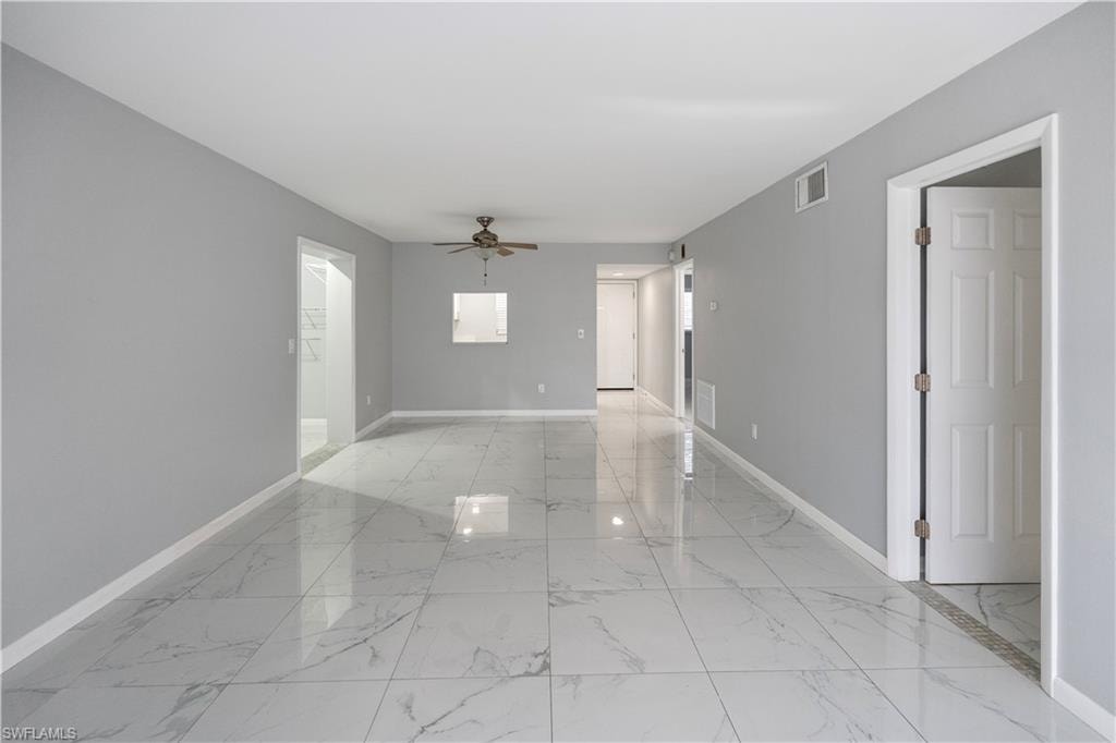 Unfurnished room with light marble finish floors and a ceiling fan