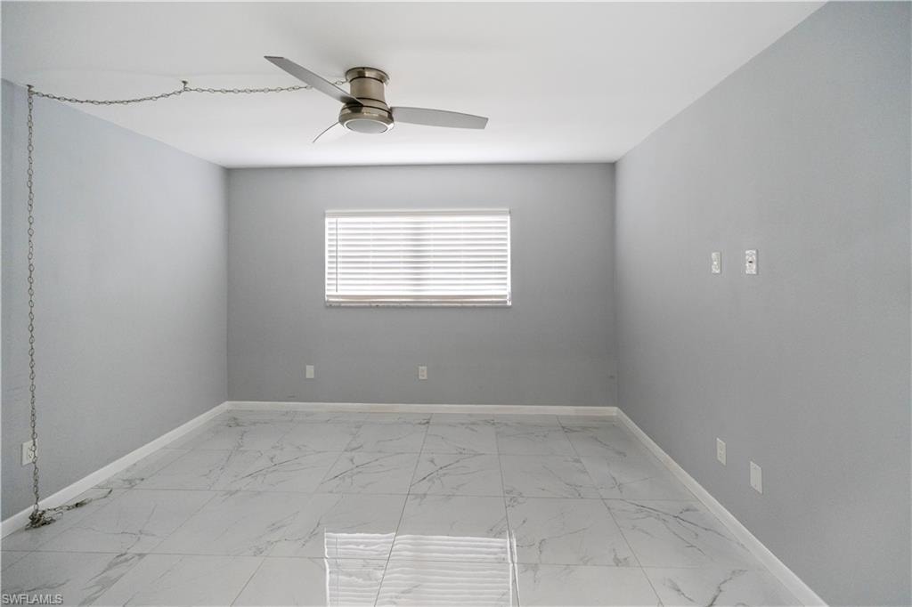Unfurnished room with light marble finish floors and ceiling fan