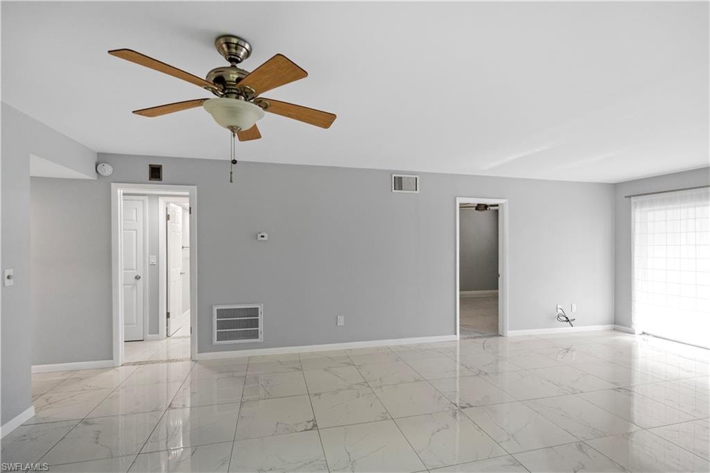 Empty room with light marble finish floors and a ceiling fan