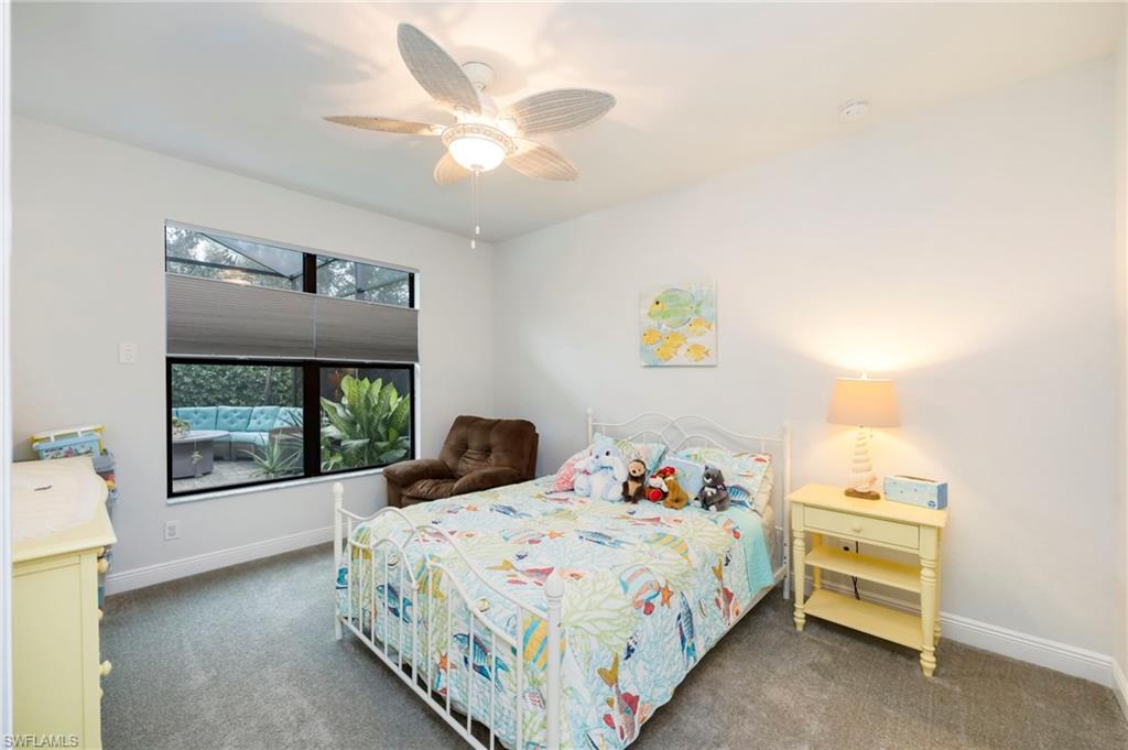 Carpeted bedroom with ceiling fan and baseboards