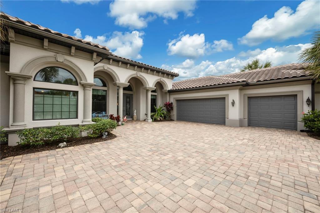 Mediterranean / spanish house with decorative driveway, a garage, stucco siding, and a tiled roof