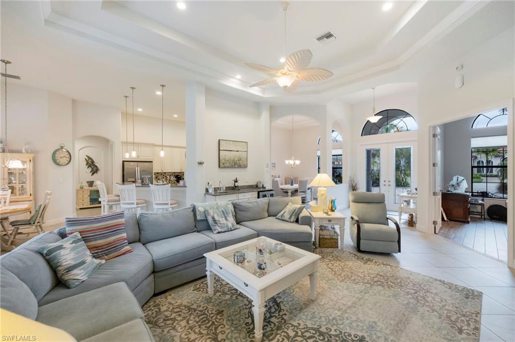 Living room with a towering ceiling, a chandelier, french doors, arched walkways, and a ceiling fan