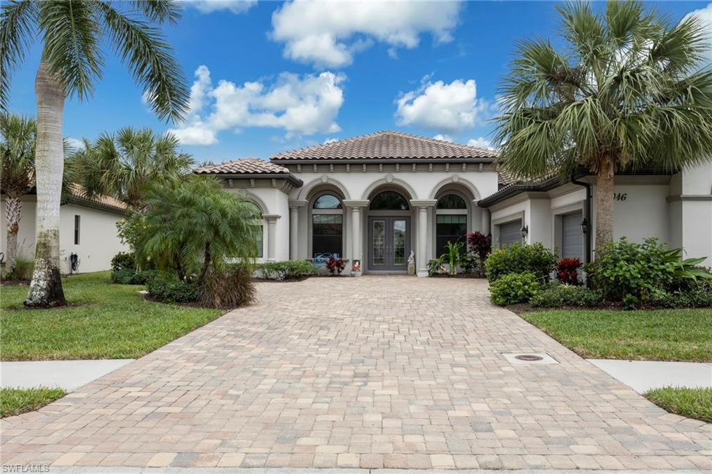 Mediterranean / spanish-style home featuring stucco siding, french doors, decorative driveway, a front yard, and a garage