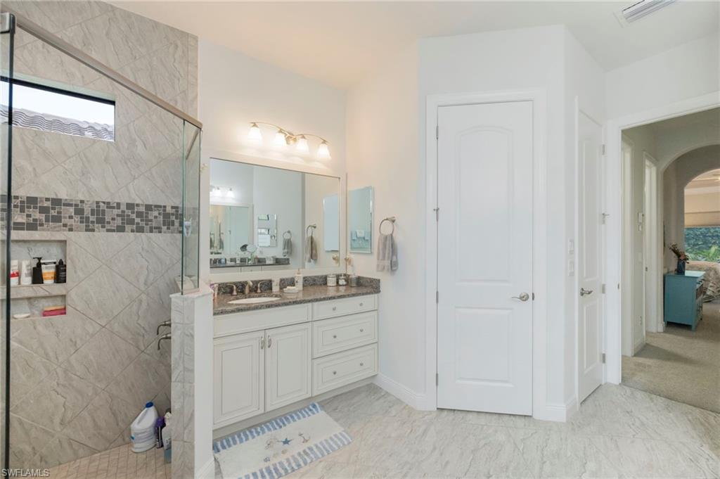 Ensuite bathroom with vanity, a stall shower, and light marble finish flooring
