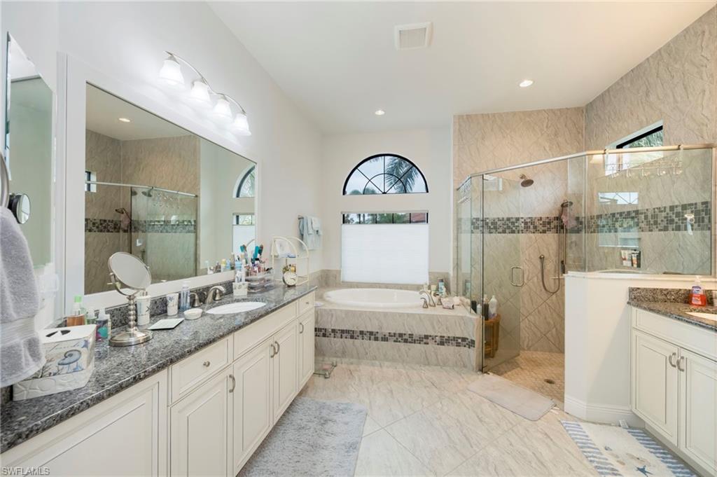 Bathroom with a bath, plenty of natural light, a stall shower, and two vanities
