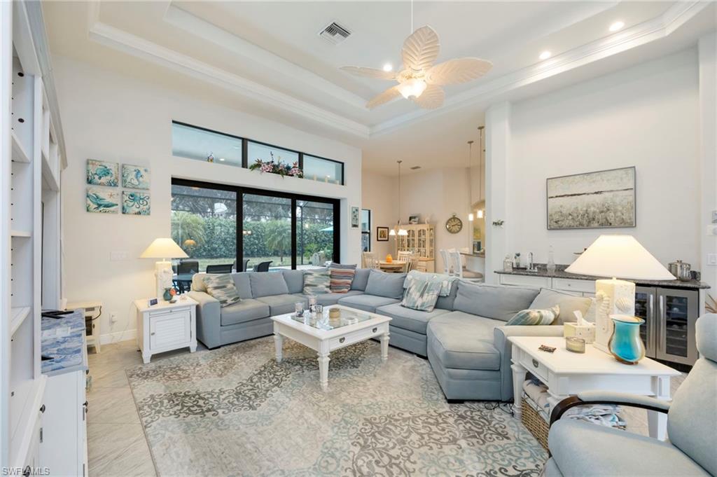 Living room featuring a towering ceiling, wine cooler, a ceiling fan, crown molding, and tile patterned flooring