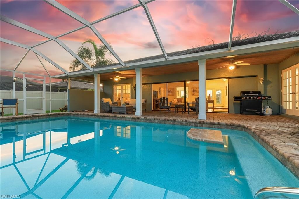 Pool at dusk with outdoor lounge area, a ceiling fan, a patio area, and grilling area