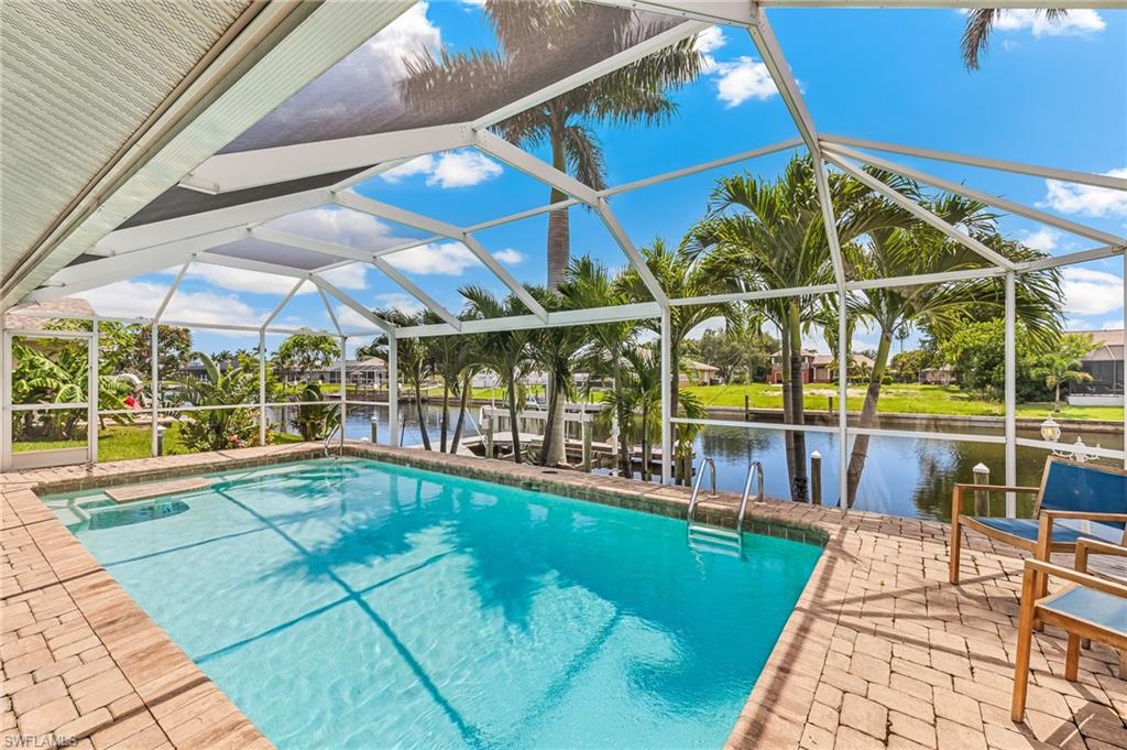 Outdoor pool featuring a water view, a patio, and glass enclosure