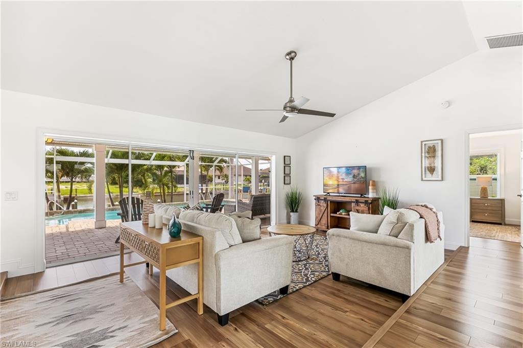 Living area with wood finished floors, a ceiling fan, healthy amount of natural light, and high vaulted ceiling