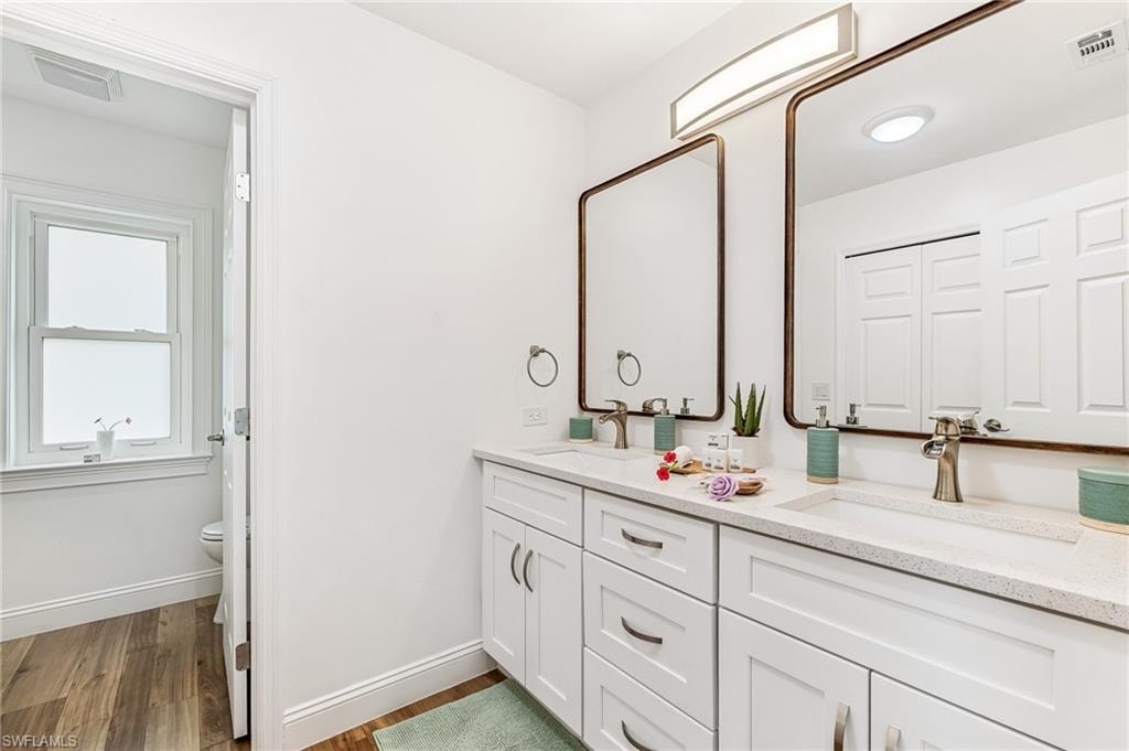 Bathroom with double vanity and wood finished floors
