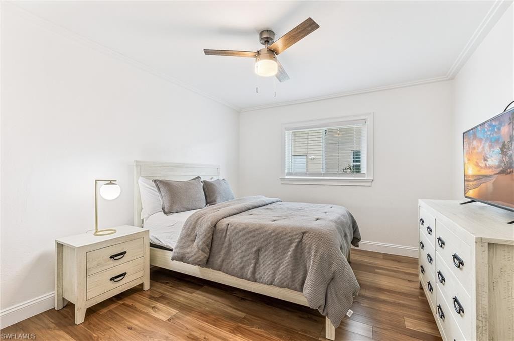 Bedroom with ornamental molding, wood finished floors, and a ceiling fan