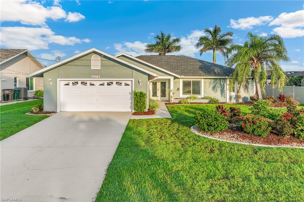 Ranch-style house featuring an attached garage, concrete driveway, a front lawn, stucco siding, and french doors