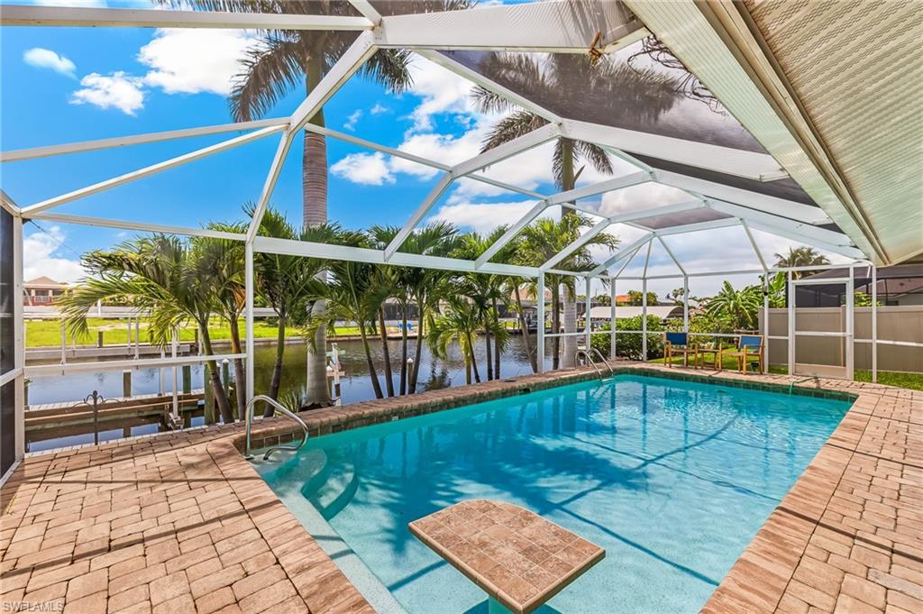 Swimming pool with a water view, glass enclosure, a patio area, and boat lift