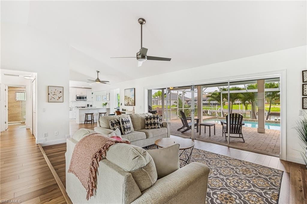 Living room featuring hardwood / wood-style floors, a ceiling fan, healthy amount of natural light, and high vaulted ceiling