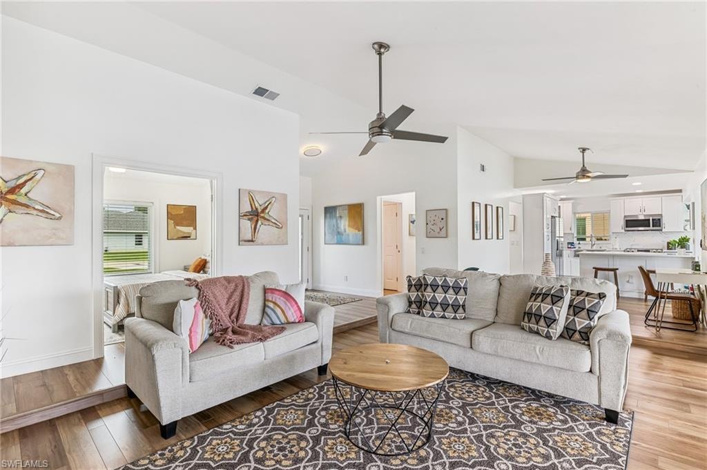 Living area with ceiling fan, light wood-style floors, and high vaulted ceiling