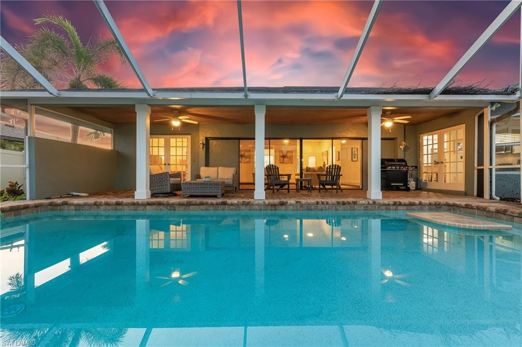 Outdoor pool featuring an outdoor hangout area, a patio area, a ceiling fan, and glass enclosure