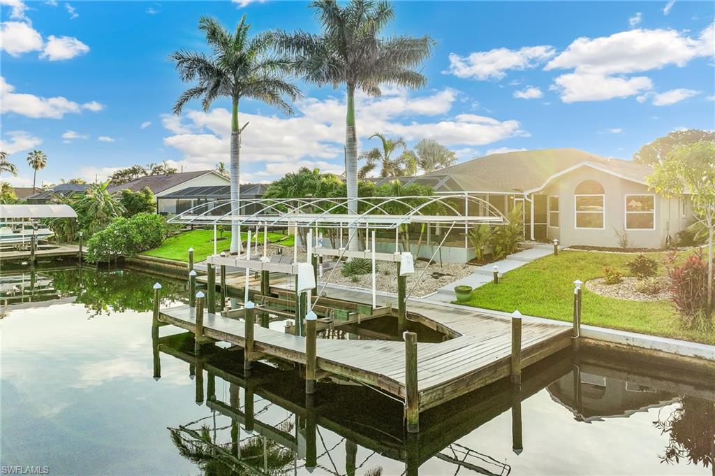 Dock with boat lift, a lawn, a lanai, and a water view