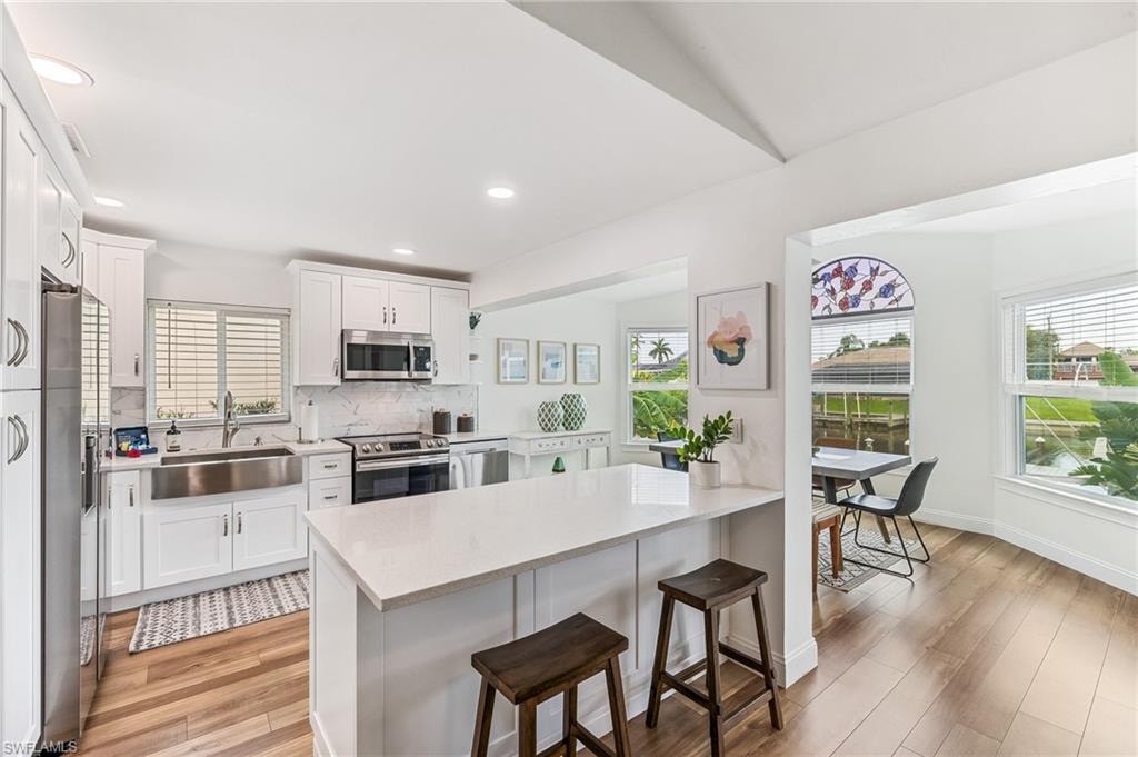 Kitchen with appliances with stainless steel finishes, a kitchen breakfast bar, light countertops, plenty of natural light, and recessed lighting