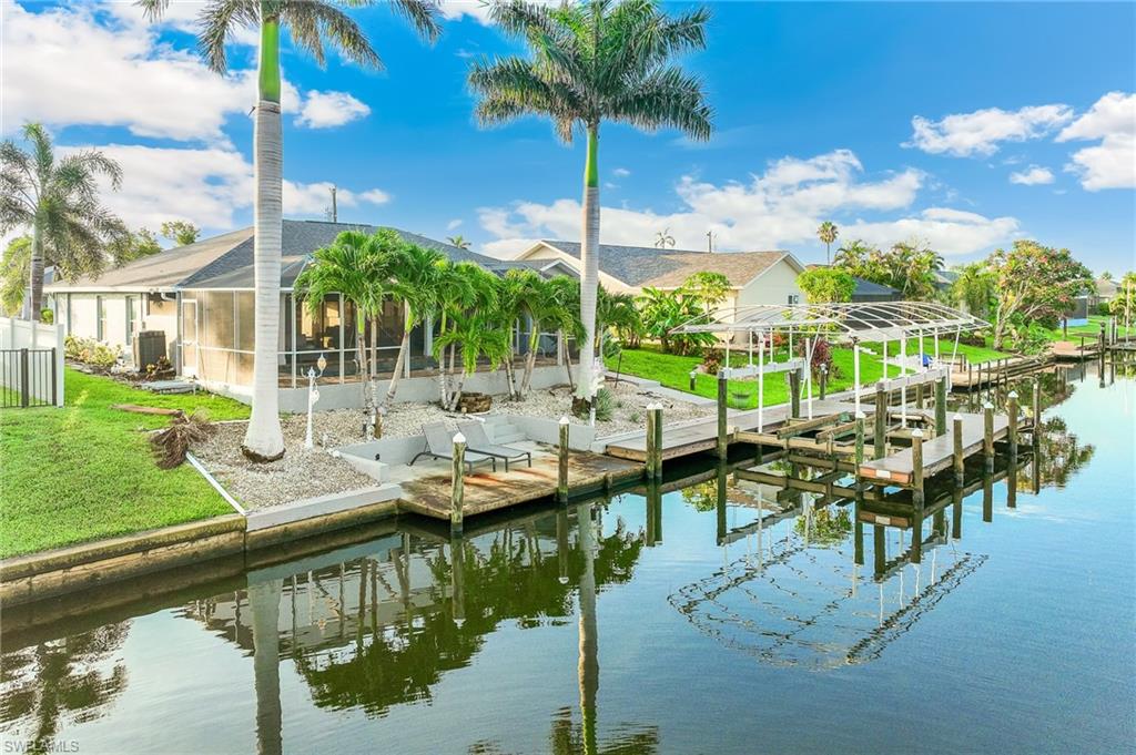 Dock area featuring a water view, boat lift, glass enclosure, and a yard