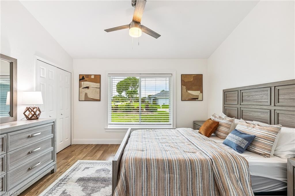 Bedroom with lofted ceiling, light wood-type flooring, a ceiling fan, and a closet