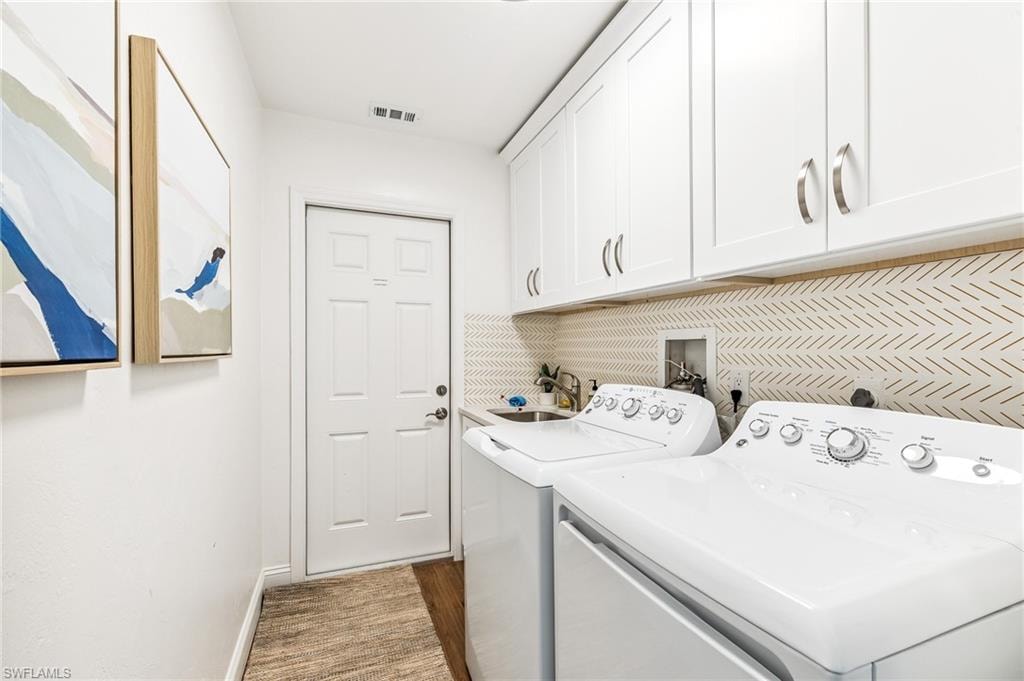 Laundry area featuring cabinet space, washer and dryer, and wood finished floors