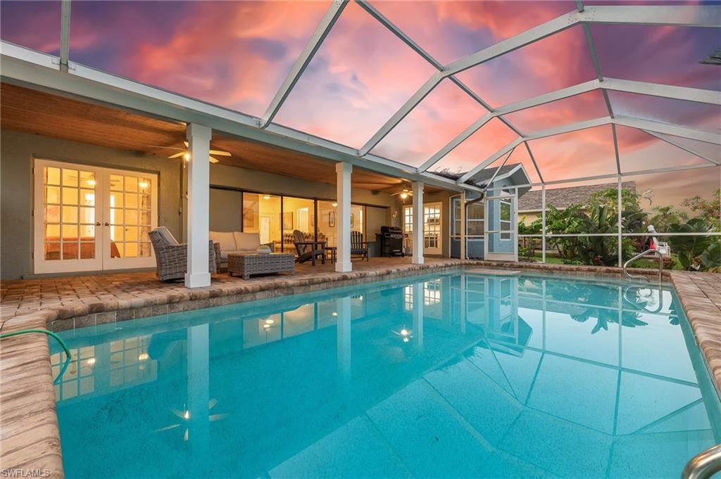 Pool at dusk with an outdoor pool, french doors, an outdoor living space, and a patio area