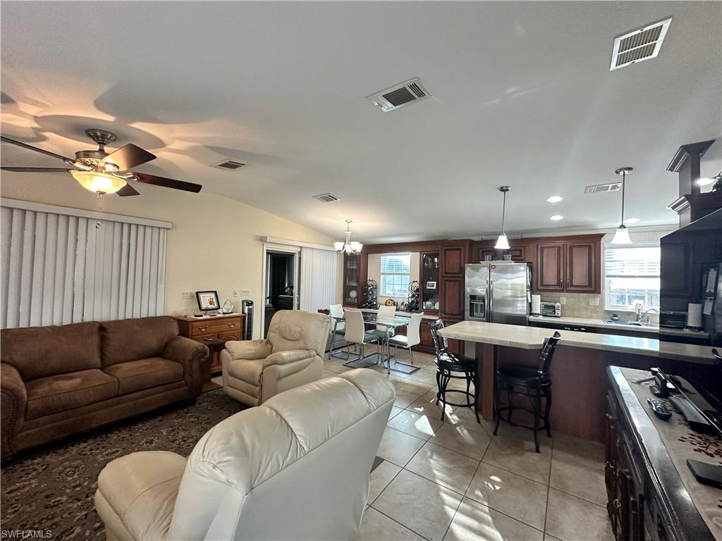 Living area featuring light tile patterned flooring, ceiling fan, lofted ceiling, a chandelier, and recessed lighting