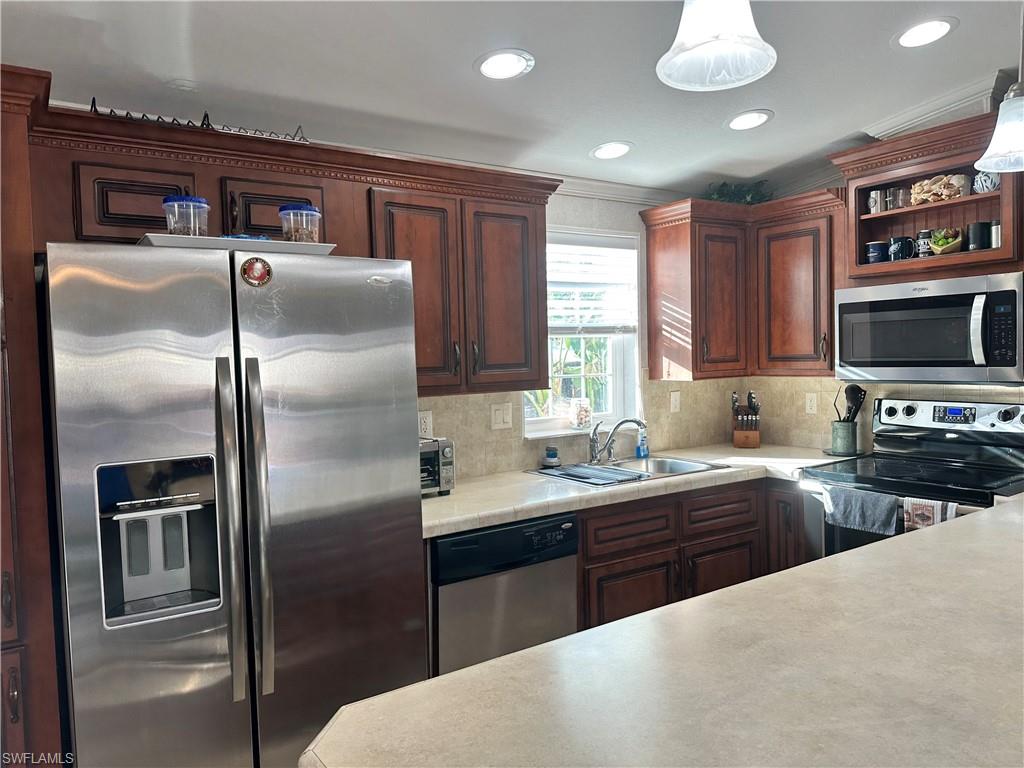Kitchen featuring appliances with stainless steel finishes, light countertops, open shelves, tasteful backsplash, and recessed lighting