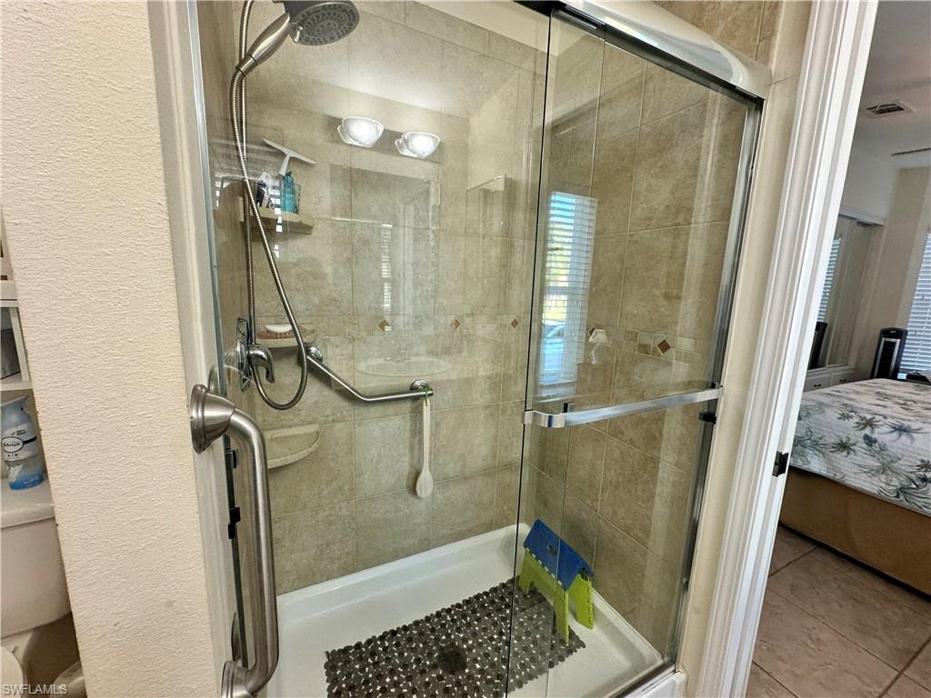 Ensuite bathroom featuring a shower stall and tile patterned flooring