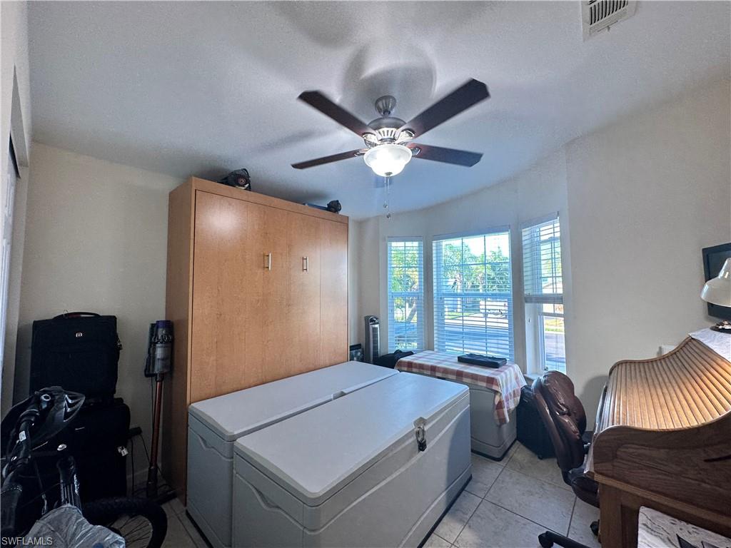 Bedroom featuring white refrigerator, light tile patterned floors, ceiling fan, and a textured ceiling