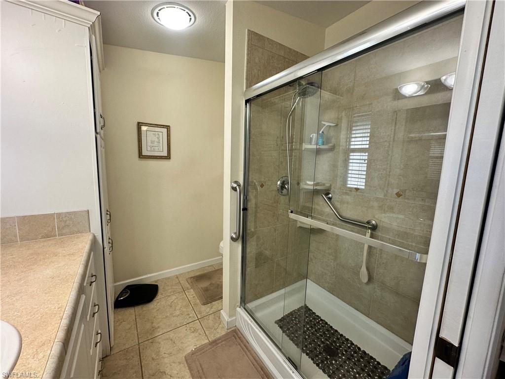 Full bathroom with vanity, a shower stall, and light tile patterned floors